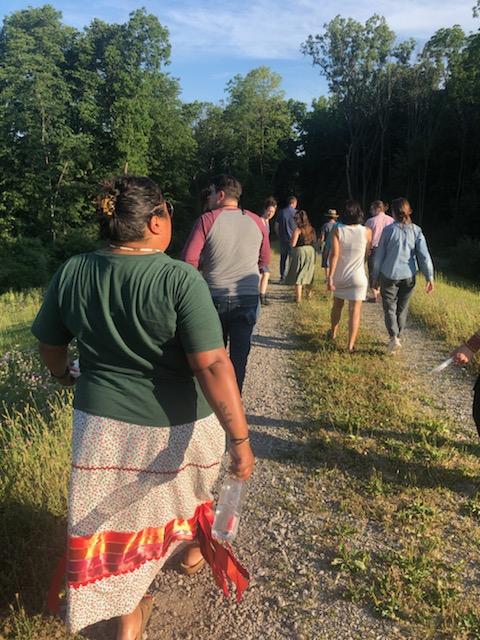 the backs of several people walking down a path into a wooded area